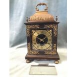 A Georgian style bracket clock in ebony case, having brass caddy shaped top framed by urn finials