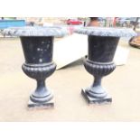 A pair of Victorian style painted cast iron garden urns with lozenge moulded overhanging rims