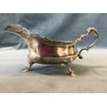 A large Edwardian, Georgian style silver gravy boat with wide spout and scrolled handle raised on