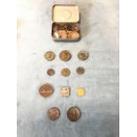 A tin containing a collection of coins and tokens including modern pennies, pre-decimal British