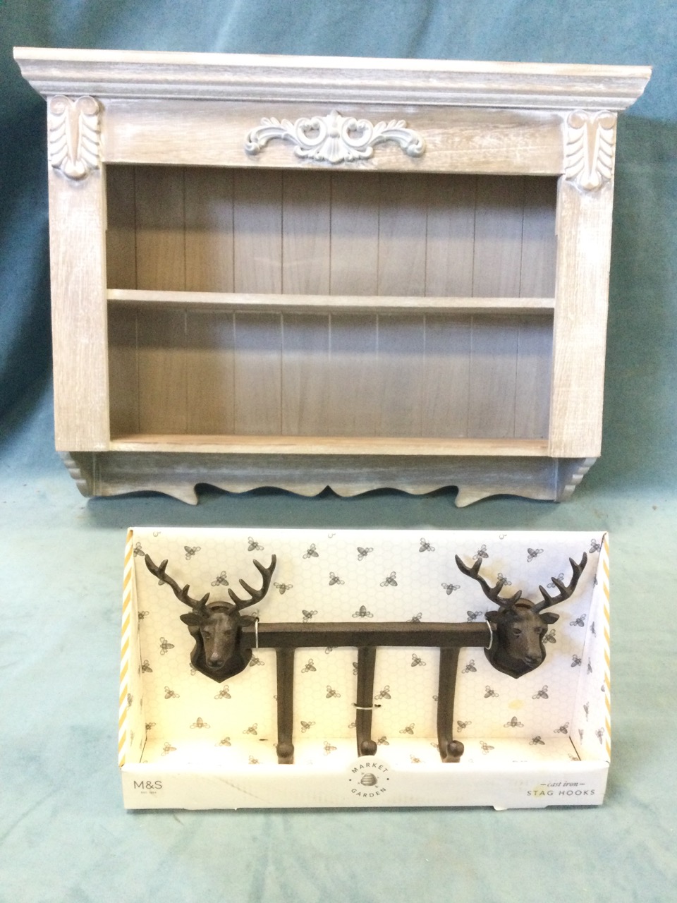 A painted wall rack with moulded cornice above open shelves having applied leaf scrolled decoration;