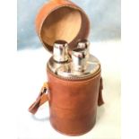A leather cased canteen fitted with three glass flasks having chromed covers with nip cups, the