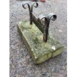 A wrought iron bootscraper, the blade on scrolled supports set into a concrete block. (18in)