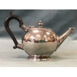 A bullet shaped hallmarked silver teapot with angled spout and ebonised wood handle on circular