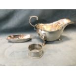 A hallmarked silver gravy boat with scrolled handle - London, 1909; a napkin ring with rope style