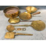 A group of brass skimmers with pierced plates, some with copper riveting; a large circular brass