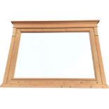 A rectangular pine overmantle mirror with moulded cornice above frame flanked by fluted columns with