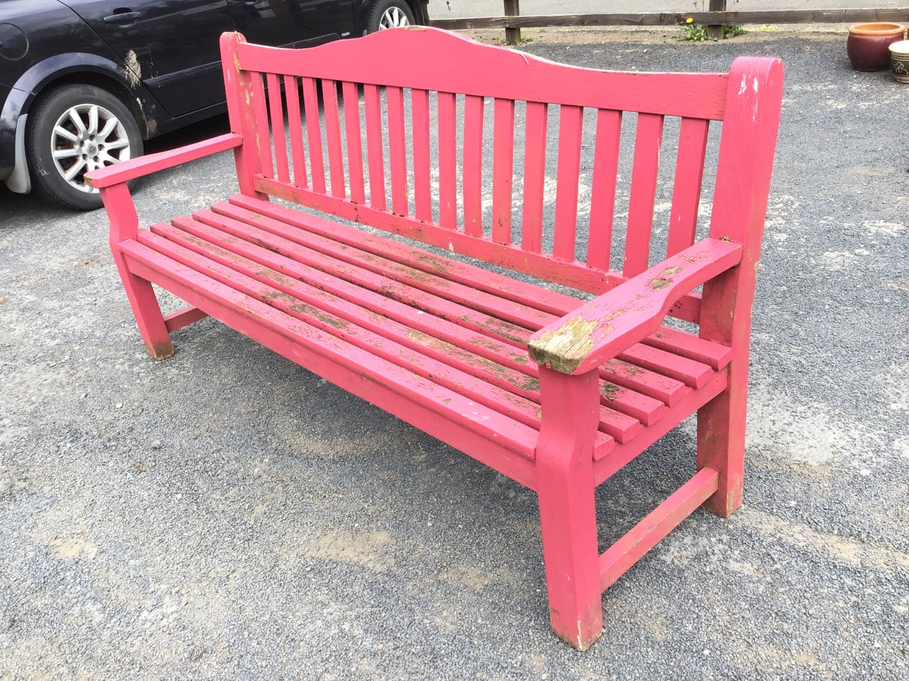 A painted teak garden bench with rectangular arched back above slats, the seat flanked by platform