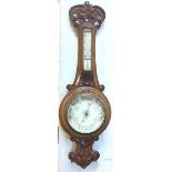 A Victorian foliate, scroll and floral carved oak aneroid wheel barometer with enamelled dial and