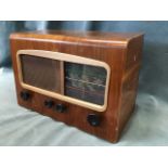 A walnut cased valve radio by Cossor Melody Maker, the case with glass dial beside speaker in