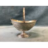An oval boat shaped hallmarked silver bon-bon dish with swing handle, embossed in relief with Indian