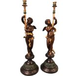A pair of large bronze candlesticks, the urn shaped candleholders on torch style columns held by