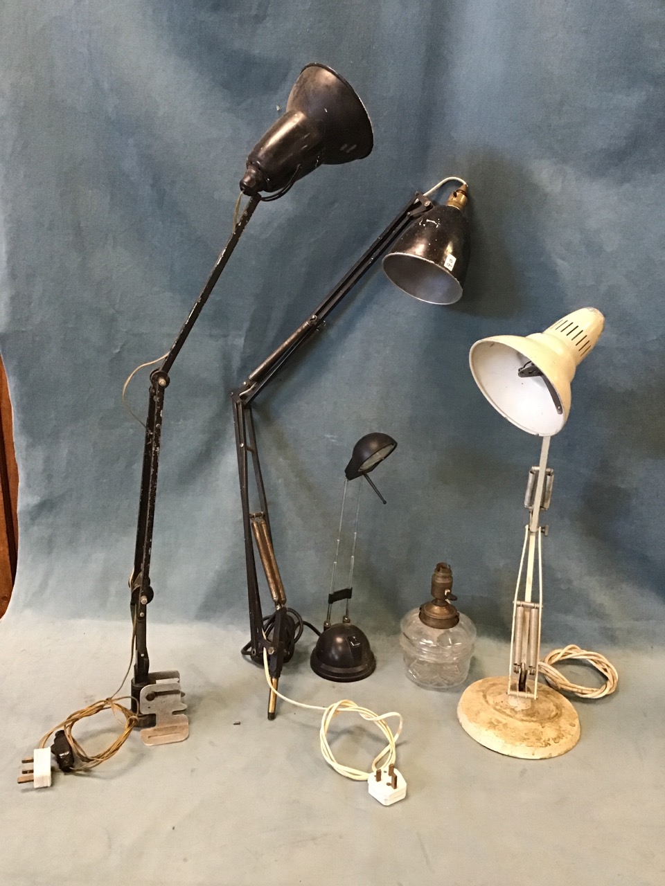 Three anglepoise type lamps, a glass oil lamp base with brass mounts converted to electricity, and