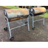 A pair of garden barbecues of tubular form, with hinged lids enclosing grills, raised on trolley