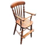 A nineteenth century elm childs chair with arched back on spindles above a solid seat, the arms with