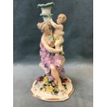 A 19th century German porcelain figural candlestick depicting a classically draped mother and