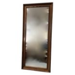 An Edwardian walnut framed bevelled mirror, with carved ribbon-type twisted border to channelled