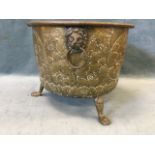 A nineteenth century embossed brass log bin raised on paw feet, the sides with lionmask ring handles