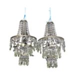 A pair of hanging glass shades with three graduated tiers of graduated crystal drops beneath swagged