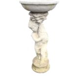 A composition stone garden birdbath with circular bowl supported by cherub holding fish above a