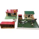 A group of vintage toy buildings comprising a farmhouse, a pigsty, a stable, a paddock and a filling