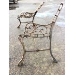 A pair of cast iron bench ends, lacking bar backs and slatted seats, with scroll cast arms and