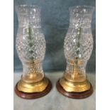 A pair of large brass candle holders on circular mahogany bases, fitted with tall bulbous cut