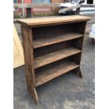 A pine open bookcase with moulded top above three rectangular shelves, with angled supports to base.