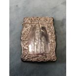 A Victorian silver card case with embossed floral and scrolling borders framing a depiction of the
