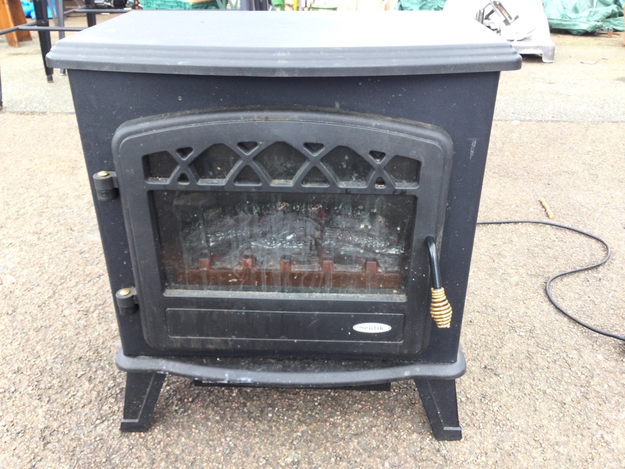 A stove type electric heater with bowfronted moulded top above an arched glazed door enclosing