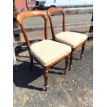 A pair of early Victorian walnut hoop-back chairs, the plain backs above over-upholstered seats,