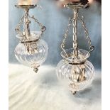 A pair of ovoid glass light fittings, the fluted vessels with chrome mounts supported by chains from