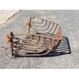 A wall-mounting cast iron hayheck with shaped tubular bars framing basket. (26in x 17in x 21in)