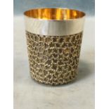 A heavy parcel-gilt silver beaker, the tapering cup with plain rim above a vermiculated gilt body,