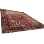 A large Iranian carpet, the central floral medallion with pendants on red ground entwined with