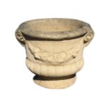A composition stone urn with lozenge cast rim above a fluted body cast with rams heads and swagged