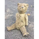A composition stone teddy bear, the seated beast with painted eyes, nose & pads. (16in)