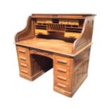 A Maple & Co oak roll-top desk, the tambour enclosing a fitted interior with compartments,