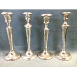 A pair of hallmarked silver candlesticks with urn shaped candleholders on tapering columns above