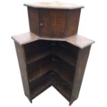 A 50s oak corner bookcase with moulded top above a small cupboard and open side shelves. (26.25in