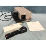 A Leica P2000 Pradovit slide projector with a hand-held controller and instruction manual.