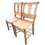 A pair of oak church chairs, the backs with pierced splats and hymnbook compartments above solid