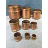 A set of nine graduated copper grain measures, the essayed vessels with brass bands manufactured