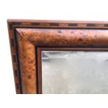 A contemporary mirror with rectangular bevelled plate in cushion moulded walnut frame within a