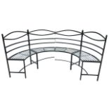 A crescent shaped metal garden bench with waved back rails above a semi-circular slatted seat,