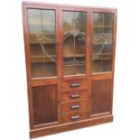 A 1930s glazed oak cabinet bookcase with three leaded glass doors enclosing shelves, above a base