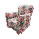 An Edwardian upholstered armchair with arched back and rounded arms framing the sprung seat, on