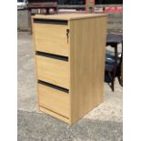 A contemporary three drawer locking filing cabinet with pale wood finish and groove pulls. (19in x