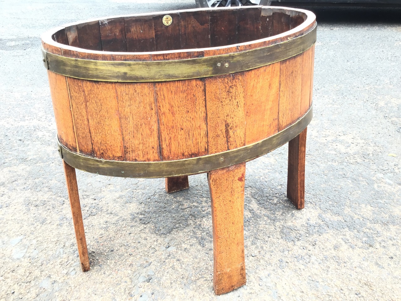 A coopered oak planter, the oval stand with brass hoops and zinc liner on stave legs, bearing makers