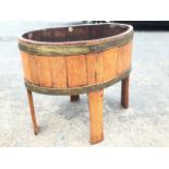 A coopered oak planter, the oval stand with brass hoops and zinc liner on stave legs, bearing makers